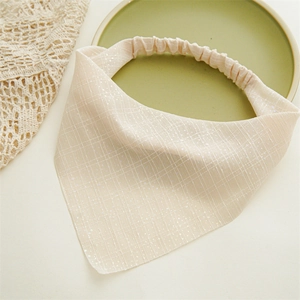 Close-up of beige elastic headscarf fabric with fine grid texture and silver glitter detail