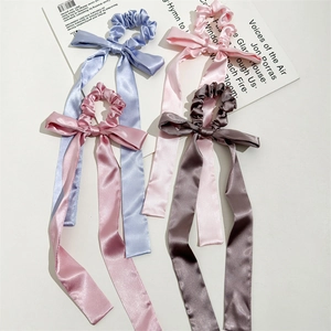 Close-up of four satin bow scrunchies in blue, pink, and coffee on a magazine