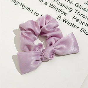 Detail of light purple satin scrunchie with silk texture and knot bow on white background