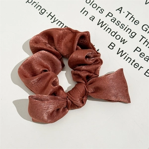 Close-up of a satin knotted scrunchie with a sleek bow in dark reddish brown