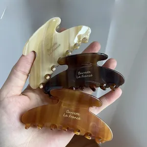 Detail of three acetate shark hair clips in tortoiseshell and amber patterns