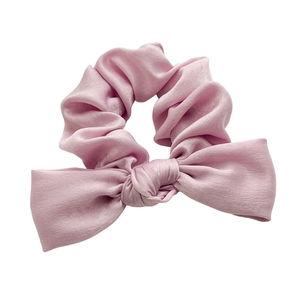 Pink satin bow scrunchie with a glossy silk-like texture and elegant knot design