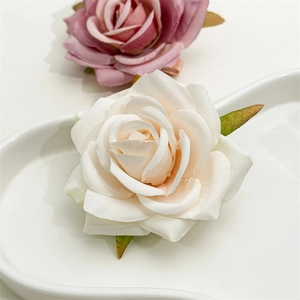 Close-up of artificial rose hair clip with soft fabric petals and realistic green leaves