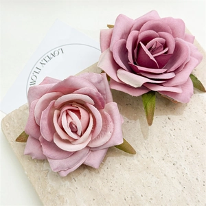 Close-up of pink and purple silk rose hair clips with green leaves on marble