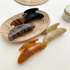 Large acetate hair claws in black, tortoiseshell, and amber patterns on a woven tray