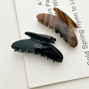 Detail view of acetate shark hair clips in glossy black and vintage tortoiseshell finish