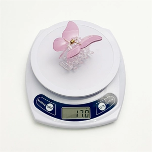 Pince à cheveux papillon rose en résine pesant 17g sur une balance électronique