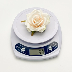 Detail of lightweight 6.3g cream white artificial rose hair clip on a digital scale