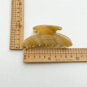 Amber marble acetate hair claw clip measuring 8.5cm shown on a scale for size