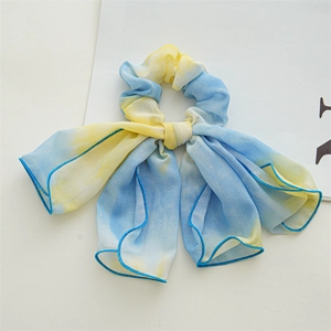 Detail of blue and yellow tie-dye chiffon hair scrunchie with elegant long ribbon tails