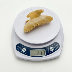 Detail showing marble texture acetic hair claw clip on scale weighing 24.4 grams
