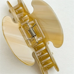 Detail view of large cream acetate hair claw clip showing durable metal spring and marble texture