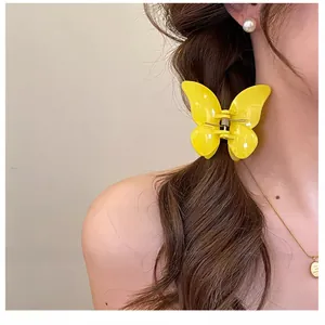 Détail d'une pince à cheveux papillon jaune vif portée sur une coiffure de femme