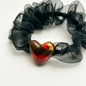 Close-up of black mesh scrunchie with a transparent red heart-shaped acrylic charm
