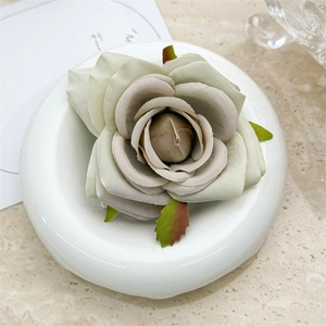 Close-up of artificial fabric rose hair clip in vintage dusty green and pink gradients