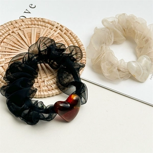 Detailed close-up of mesh scrunchies with heart pendants in black and beige colors