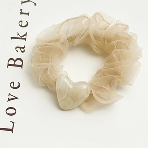 Detail of beige organza mesh hair scrunchie with a textured heart pendant charm