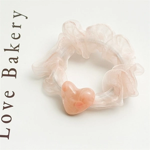 Detail shot of a peach mesh hair scrunchie with a marbled resin heart charm decoration