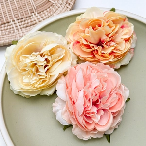 Dettaglio di fermagli per capelli con peonie artificiali e petali in tessuto colorati