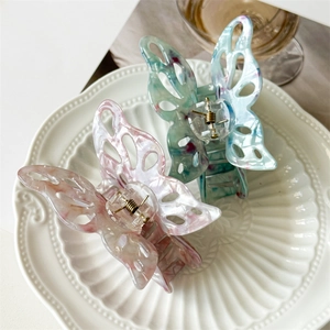 Detailed macro view of hollow butterfly hair claws in pink and blue marble finish
