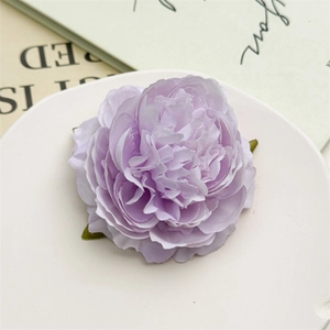 Dettaglio fermaglio per capelli peonia in seta viola chiaro con foglie su piatto bianco