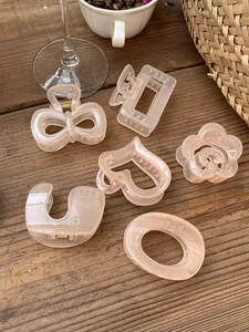 Detailed set of 6 pink resin hair claws in various geometric shapes on a wooden surface