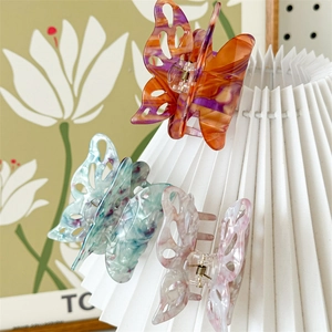 Detailed view of three hollow butterfly hair claws in marble and floral patterns