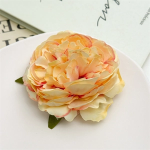 Dettaglio di fermaglio per capelli a peonia con petali sfumati e foglie su piatto bianco