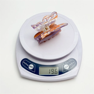 Large butterfly hair claw clip with purple marble pattern on a digital scale weighing 19.6g