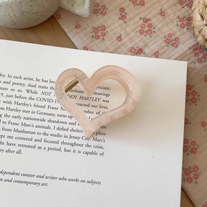 Macro view of heart-shaped peach pink acetate hair claw clip with marble texture