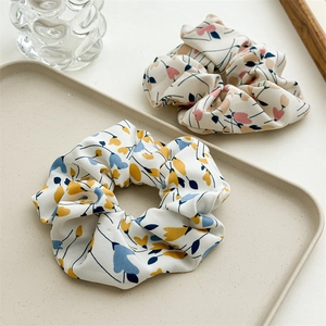 Close-up of floral print scrunchies in cream tray with elegant minimalist backdrop