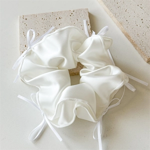 Chouchou élégant en satin blanc avec nœuds délicats sur un support minimaliste chic