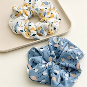 Detail view of two floral scrunchies in white and blue chiffon with delicate flower patterns