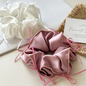 Détail de chouchous en satin blanc et rose poudré avec nœuds de ruban élégants