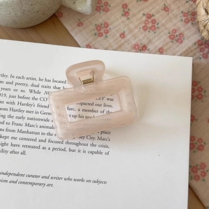 Detailed view of the pink translucent rectangular hair claw clip on a book page