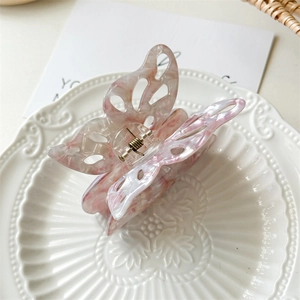 Detailed macro view of hollow butterfly hair claw in pink marble acetate finish