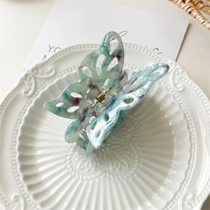 Detailed view of butterfly hair claw clip with blue marble texture and hollow-out wings