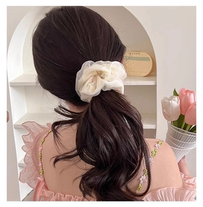 Detail of a beige chiffon scrunchie worn on a ponytail for an elegant hairstyle