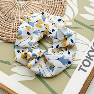Detail of floral scrunchie with yellow and blue flowers on natural woven texture
