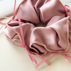 Détail du chouchou en satin rose avec nœud ruban montrant une texture soyeuse