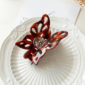 Detail of hollow butterfly hair claw clip with amber tortoise shell pattern on ceramic plate