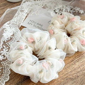 Detailed macro view of cream organza hair scrunchie with pink 3D rose embroidery