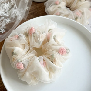 Detail of rose mesh hair scrunchies with pink floral ribbon and green leaves garnish