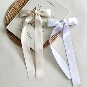Détail de nœuds à cheveux en satin élégants beige et blanc sur fond de livre vintage