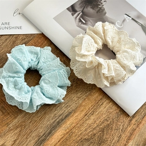 Detailansicht von hellblauen und cremefarbenen Spitzen-Scrunchies mit Stickerei und Schleifen