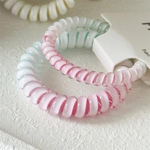 Makroaufnahme von stylischen Spiralgummis mit Farbverlauf in Pink und Blau auf Steinhintergrund