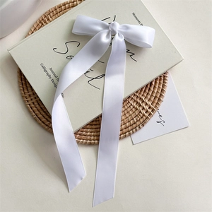 Détail d'un nœud papillon en satin blanc avec de longs rubans sur un bureau épuré
