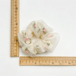 Floral organza hair scrunchie with 3D rose decor measured on a wooden scale