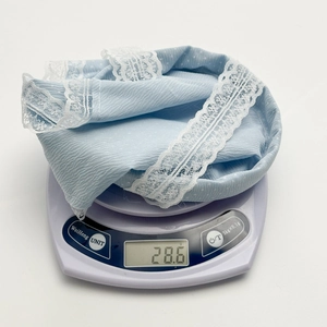 Détail du tissu gaufré bleu clair et de la bordure en dentelle blanche du bandeau