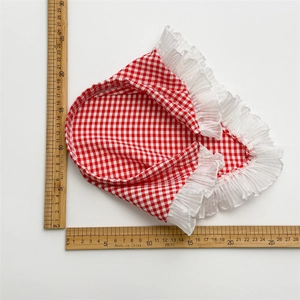 Bandeau à carreaux rouge et blanc avec dentelle plissée blanche, mesuré par une règle en bois